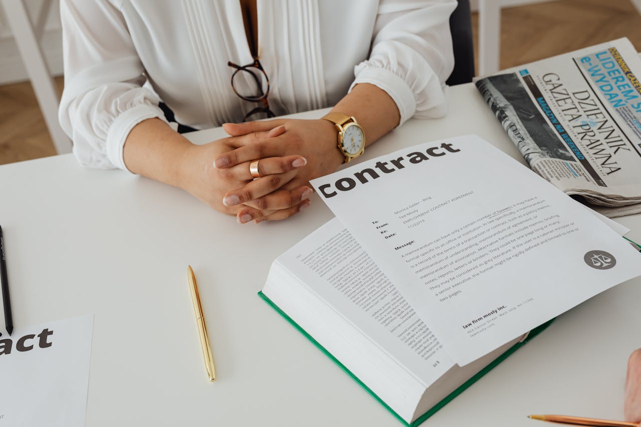 about-01 Businesswoman sitting at desk reviewing contract with legal documents and newspaper.